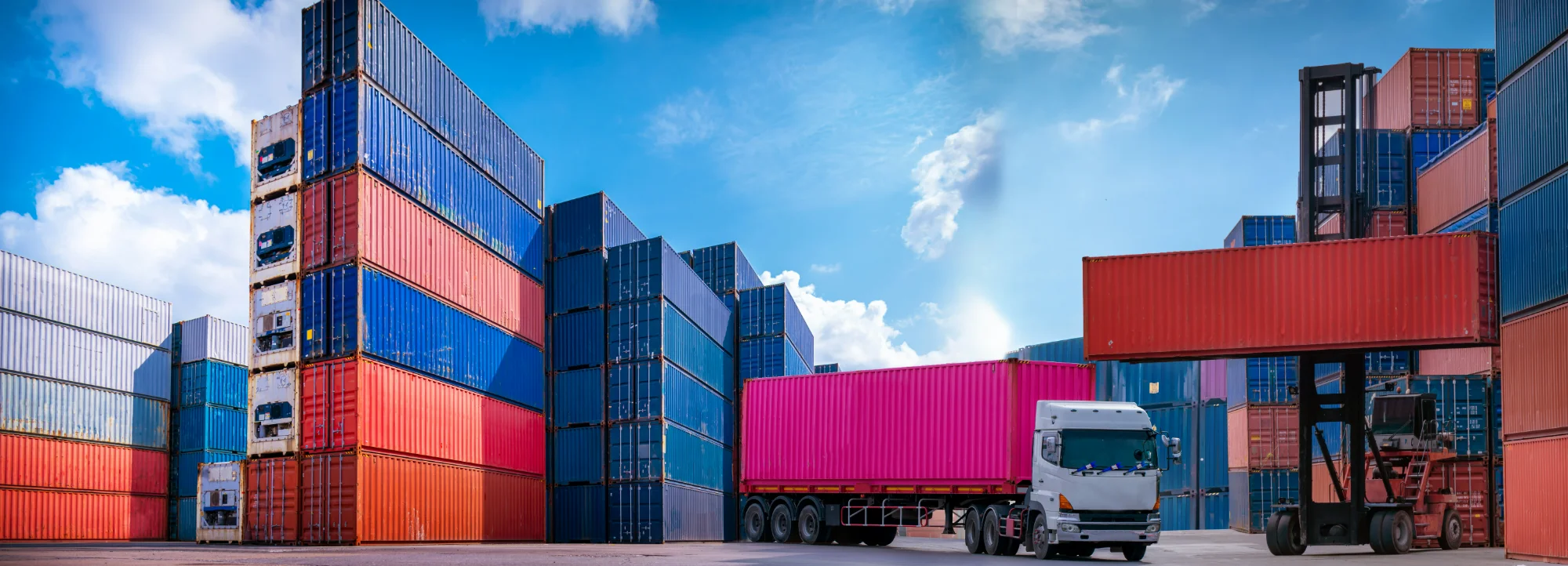 Semi truck driving through a busy shipping container terminal representing America's truck parking shortage.